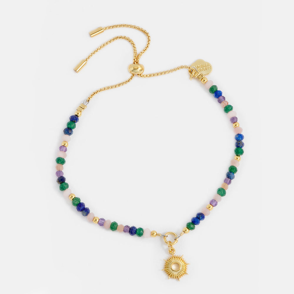 Multicolored beaded bracelet with gold sun charm & clasp on a white background
