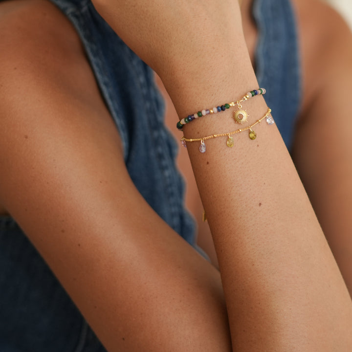 Close-up of a person's arm wearing multiple bracelets with beads and gold accents.