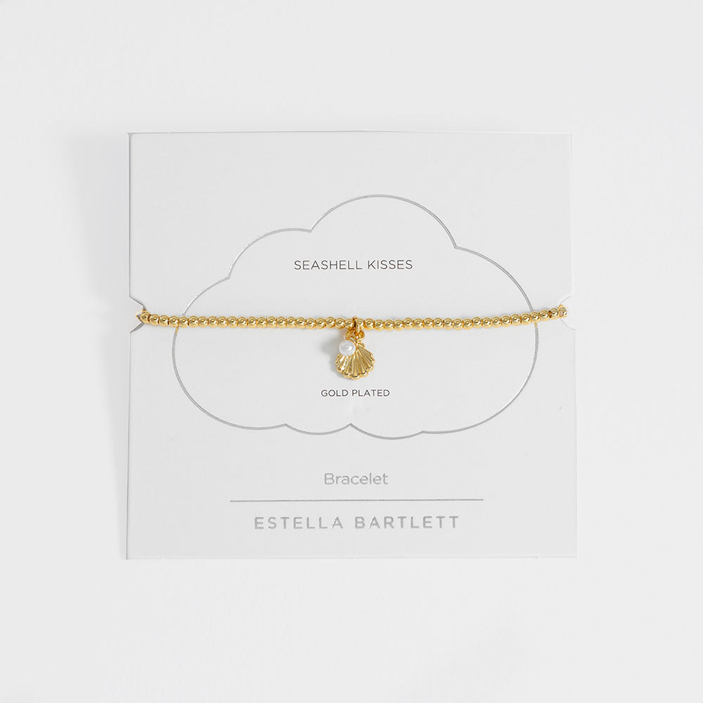 Gold-plated bracelet with seashell charm on a white card with 'Estella Bartlett' branding.