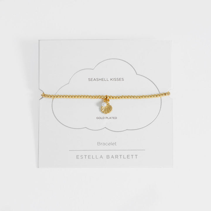 Gold-plated bracelet with seashell charm on a white card with 'Estella Bartlett' branding.
