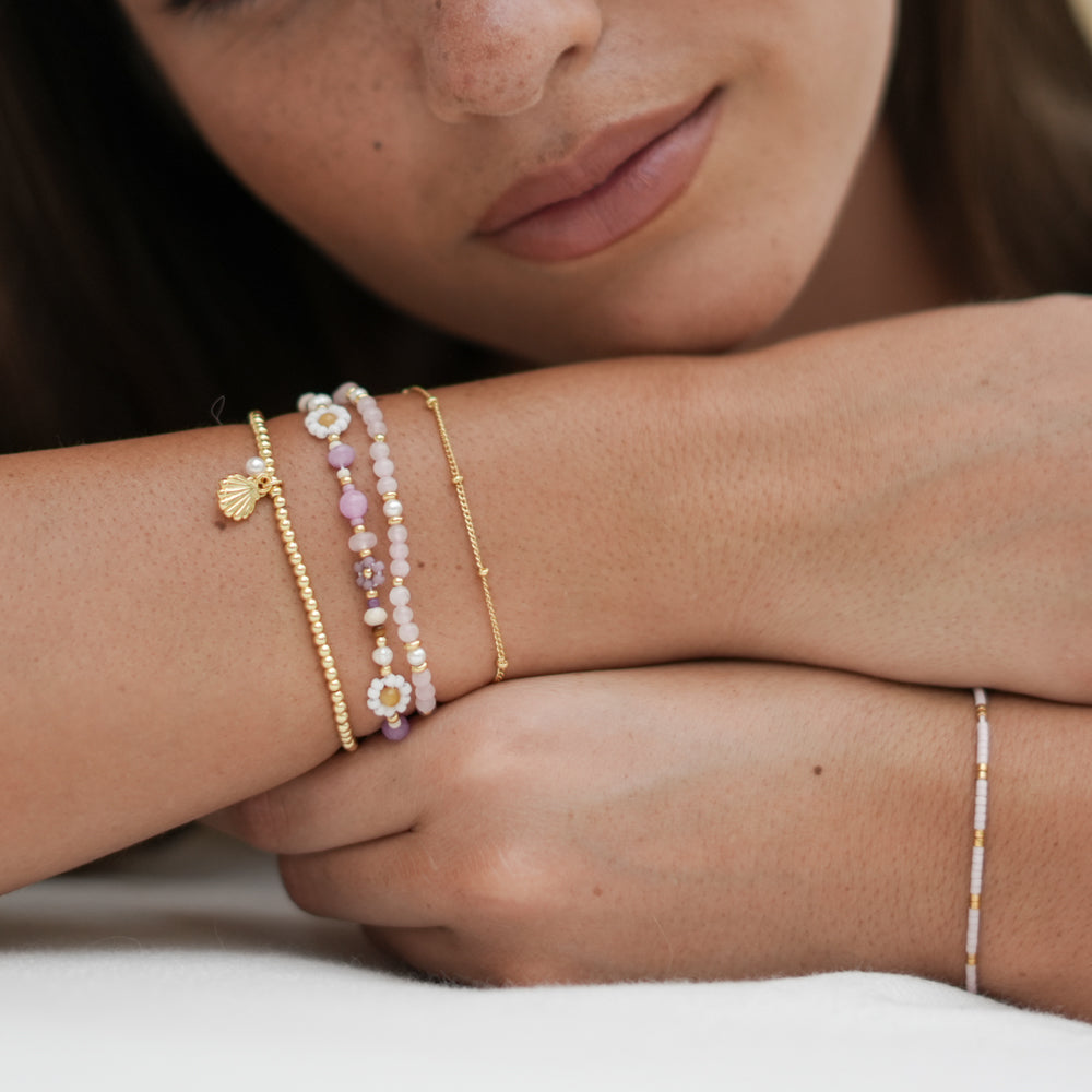 Close-up of a person's wrist wearing multiple bracelets with a neutral background
