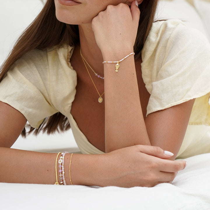 Woman wearing multiple gold bracelets on a white background