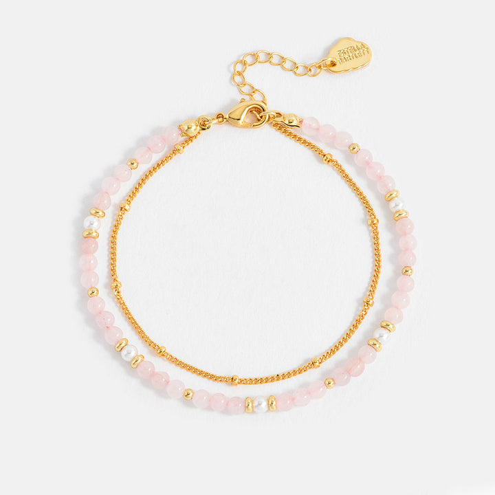 Two layered bracelets with pink beads and gold accents on a white background