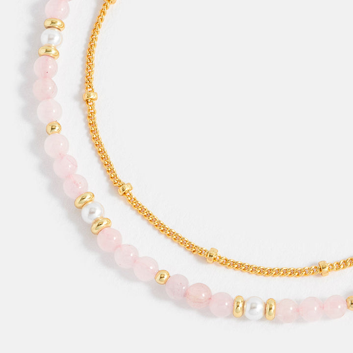 bracelet with pink beads and gold chain on a white background