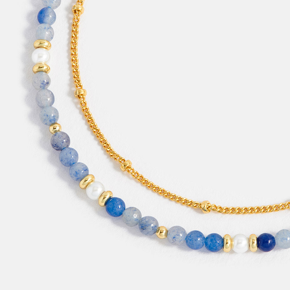 bracelet with blue and white beaded chain and gold accents on a white background