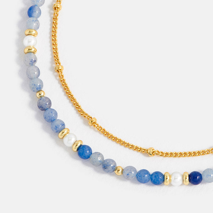 bracelet with blue and white beaded chain and gold accents on a white background