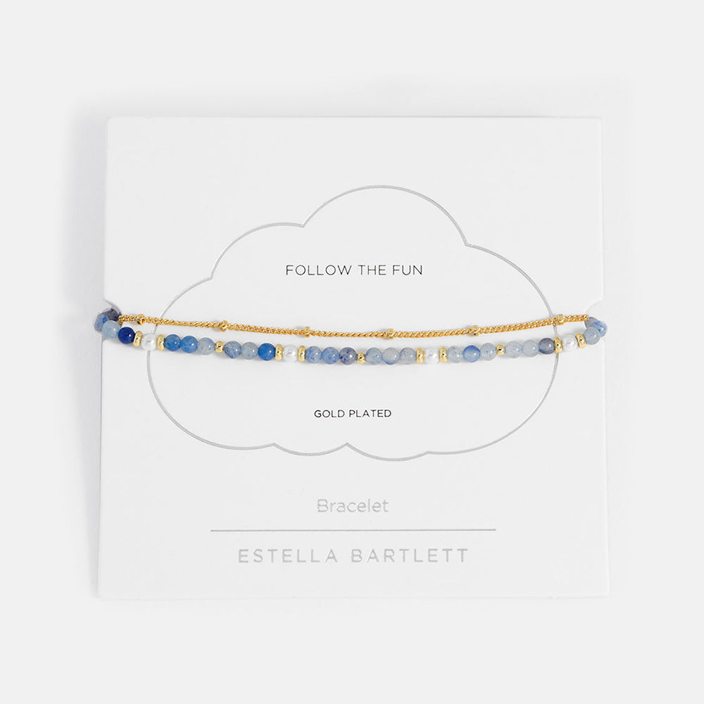 Gold-plated bracelet with blue beads on a white card with branding information.