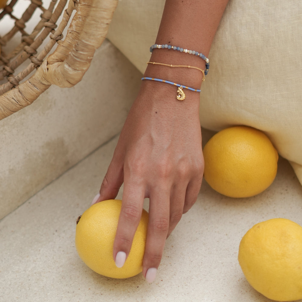 Hand with bracelets holding a lemon, with more lemons in the background