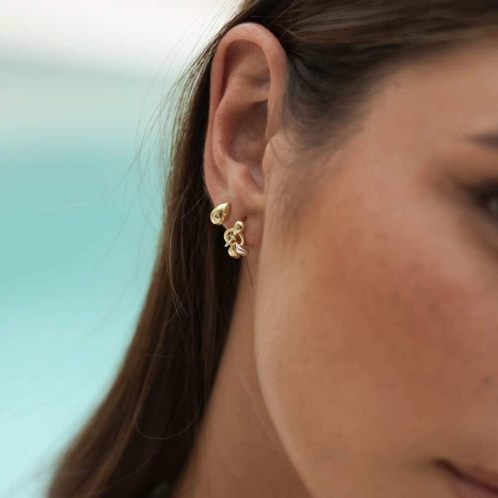 woman wearing 2 gold earrings, one teardrop shaped