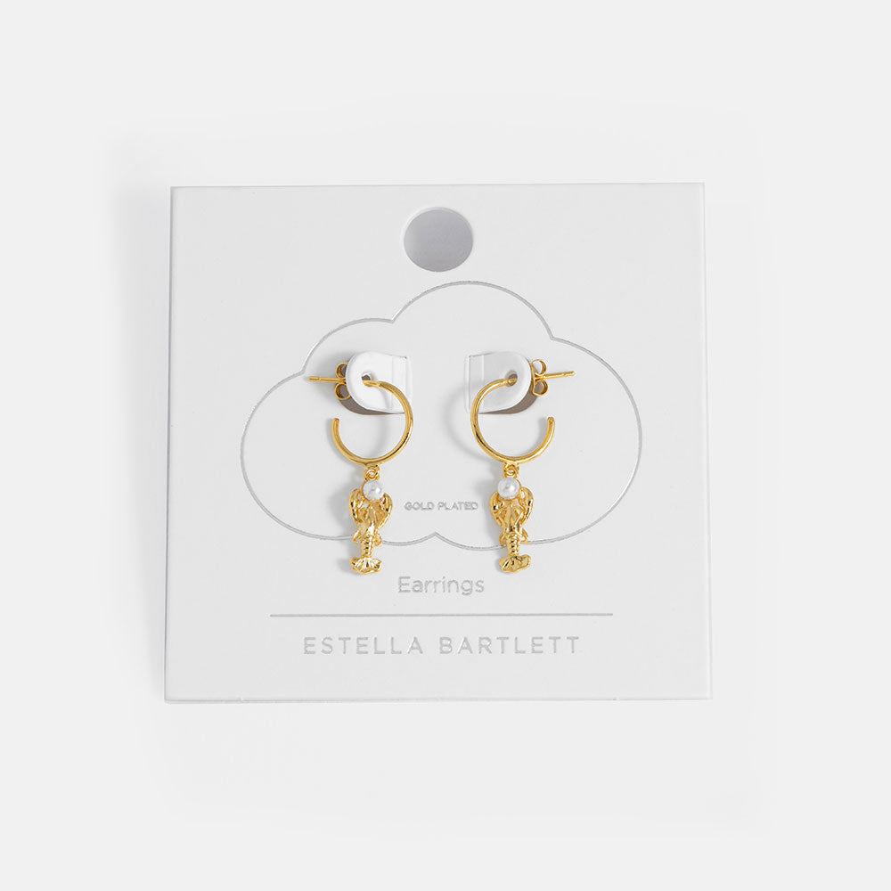 Gold earrings with pearl accents on a white card with 'Estella Bartlett' branding.
