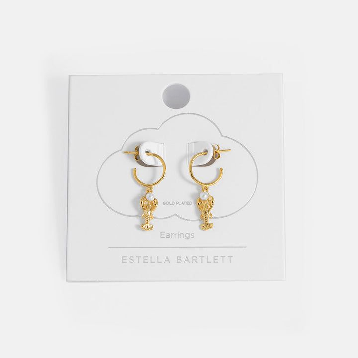 Gold earrings with pearl accents on a white card with 'Estella Bartlett' branding.