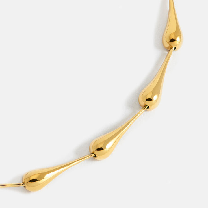 gold drop link bracelet on light grey background