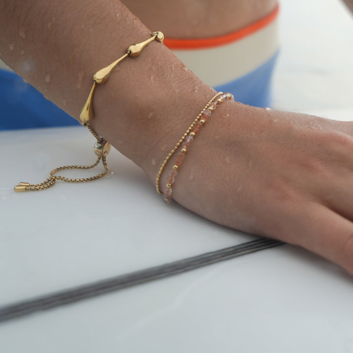 person wearing gold drop link bracelet