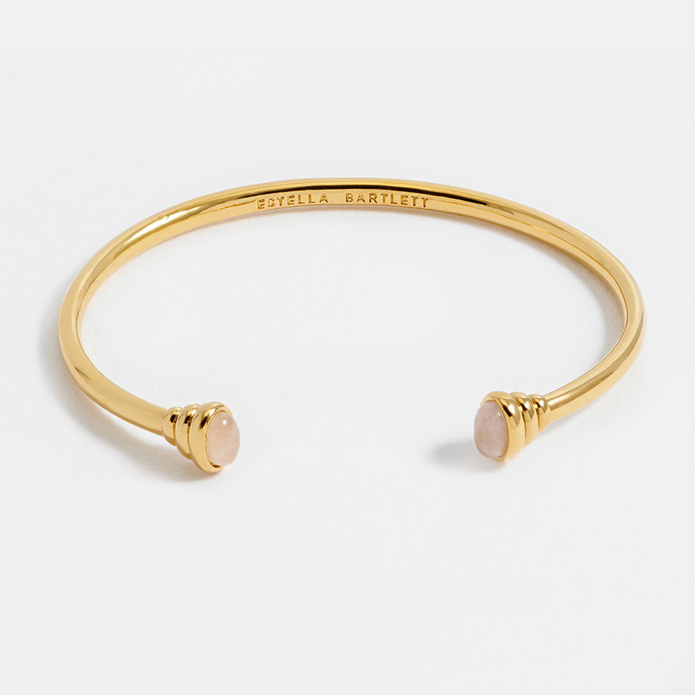 gold bangle bracelet with graduated ends with light pink gemstones