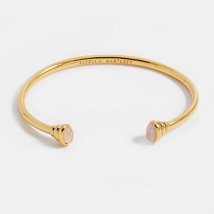 gold bangle bracelet with graduated ends with light pink gemstones