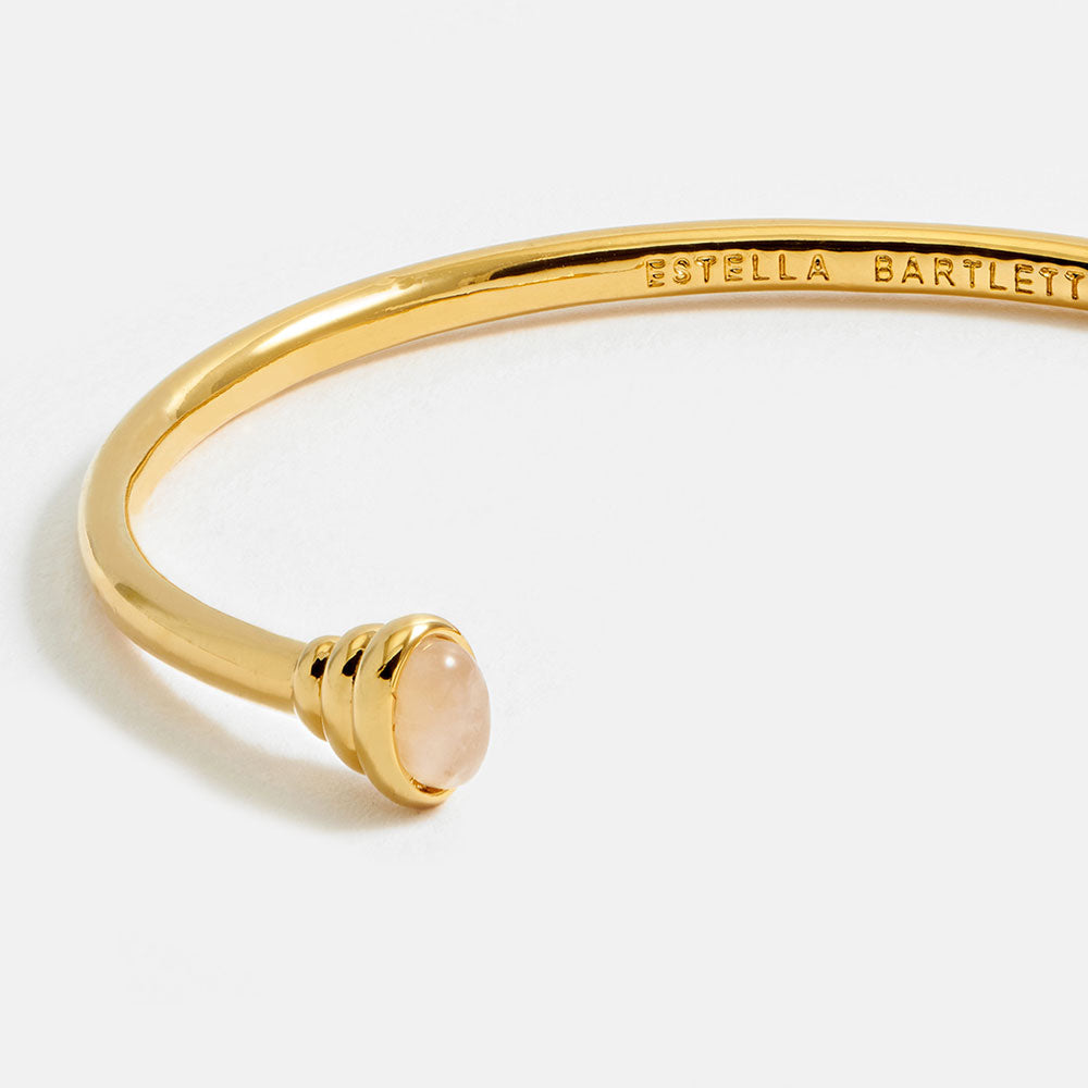 gold bangle bracelet with graduated ends with light pink gemstones