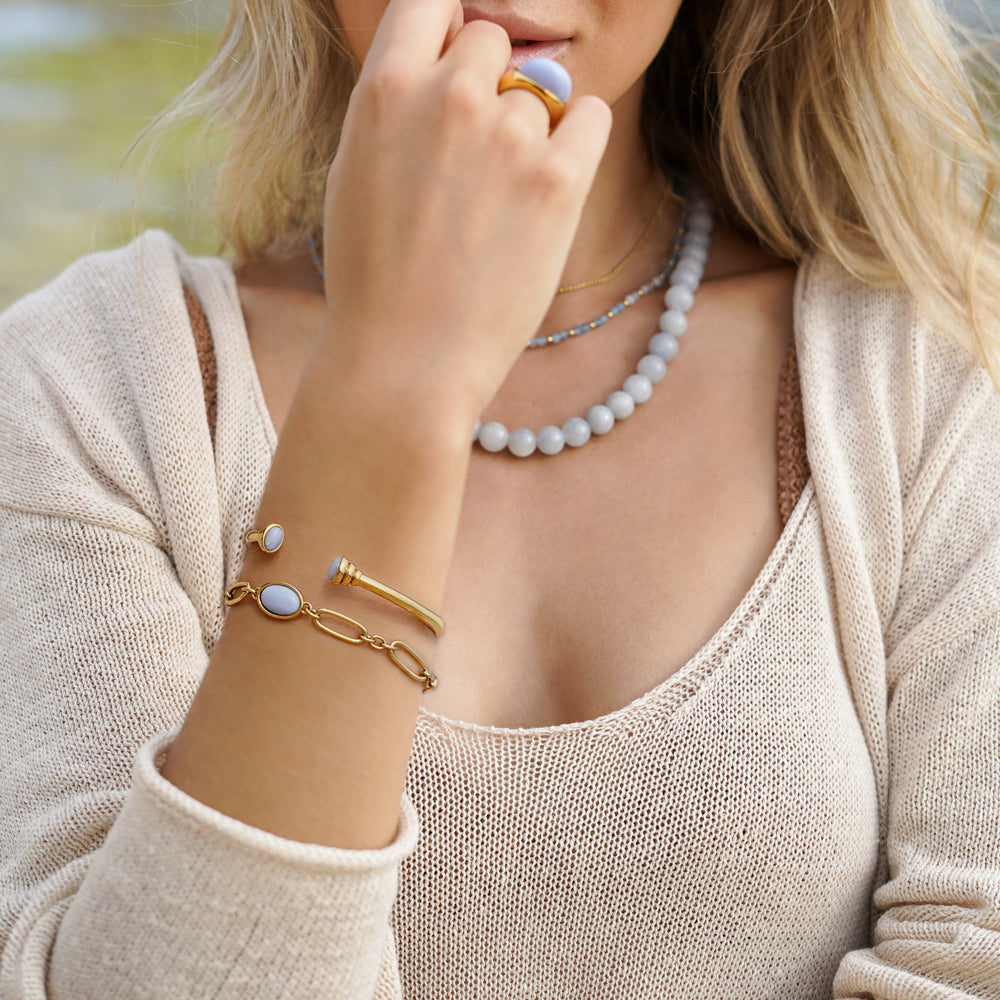 gold bangle bracelet with graduated ends with light blue gemstones