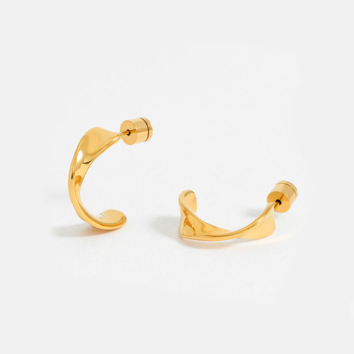 Gold twist hoop earrings on a light grey background