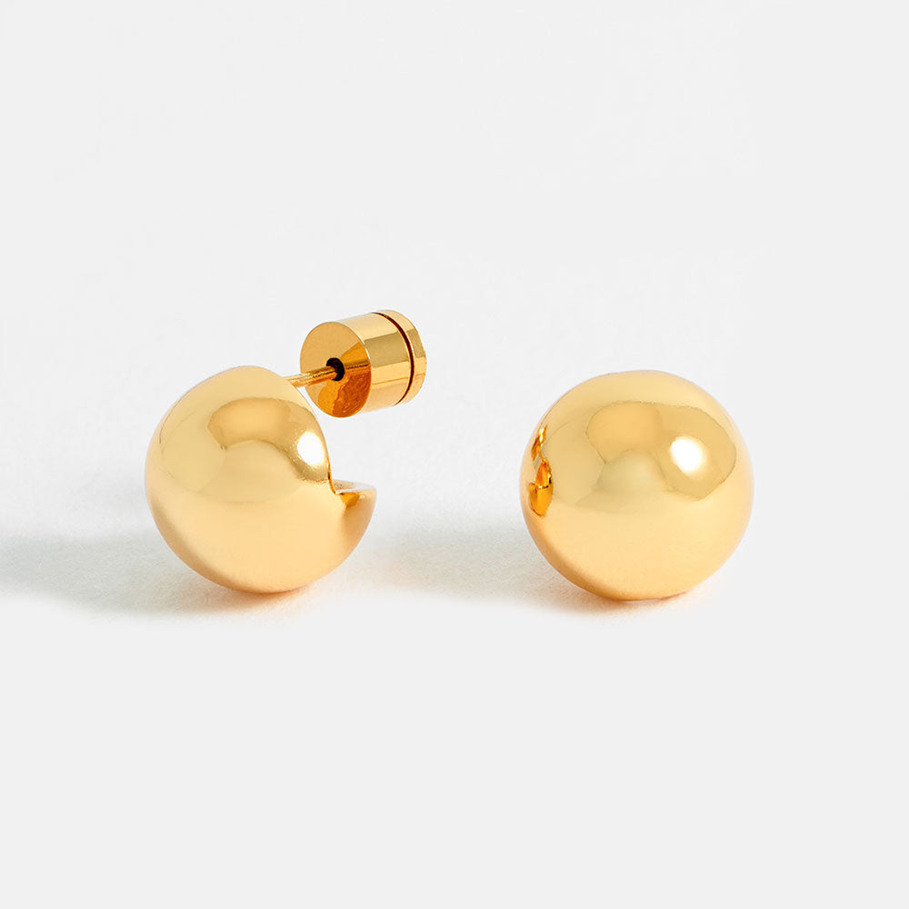Gold sphere stud earrings on a light grey background