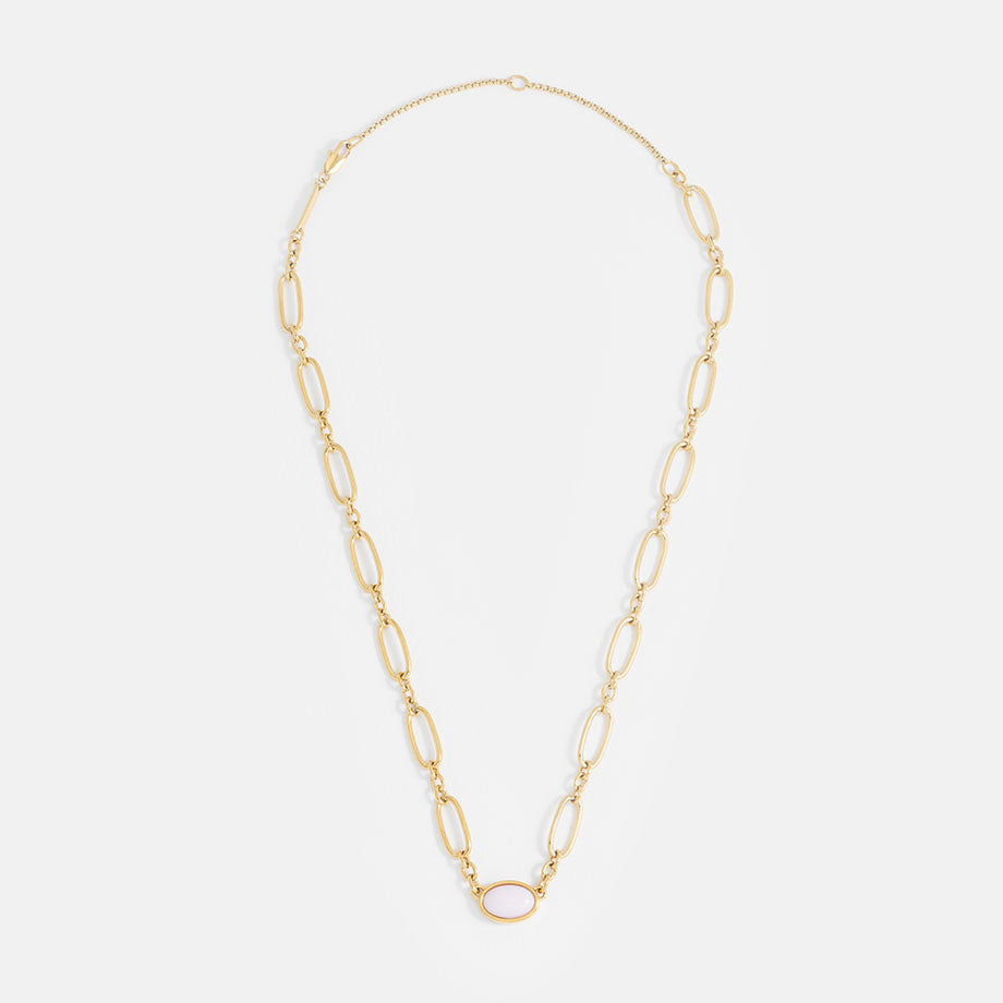 Gold chain necklace with a pink oval gemstone on a light grey background