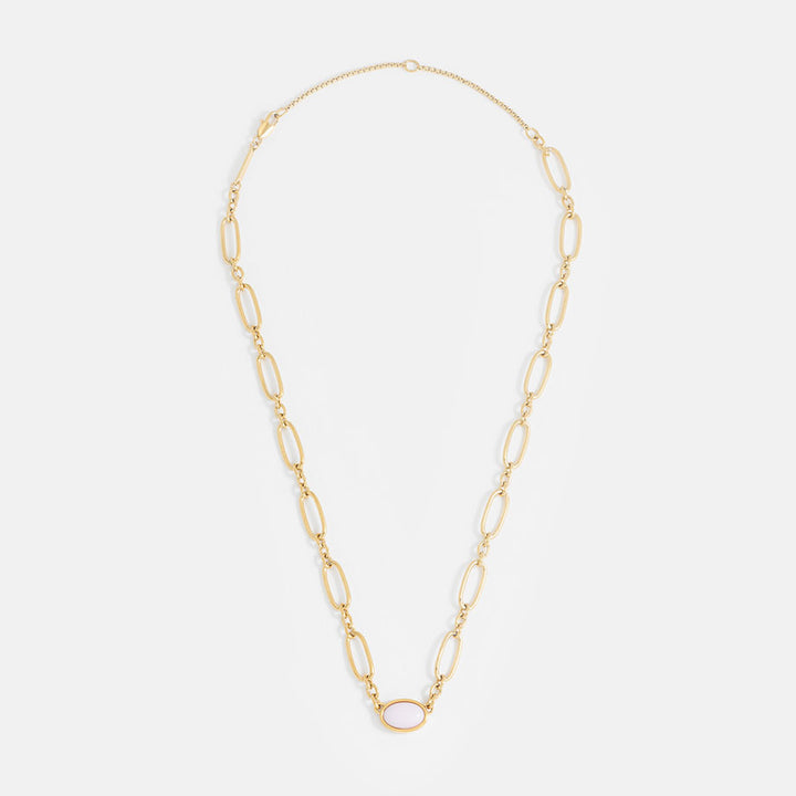 Gold chain necklace with a pink oval gemstone on a light grey background
