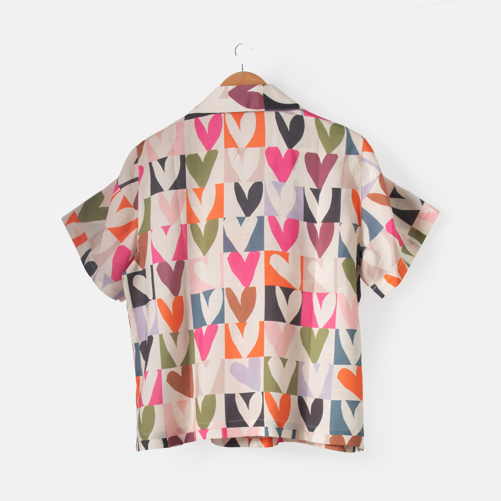 Colorful heart-patterned shirt on a hanger against a white background