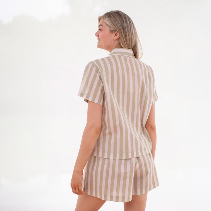 Woman wearing a green and light pink striped pajama set on a white background
