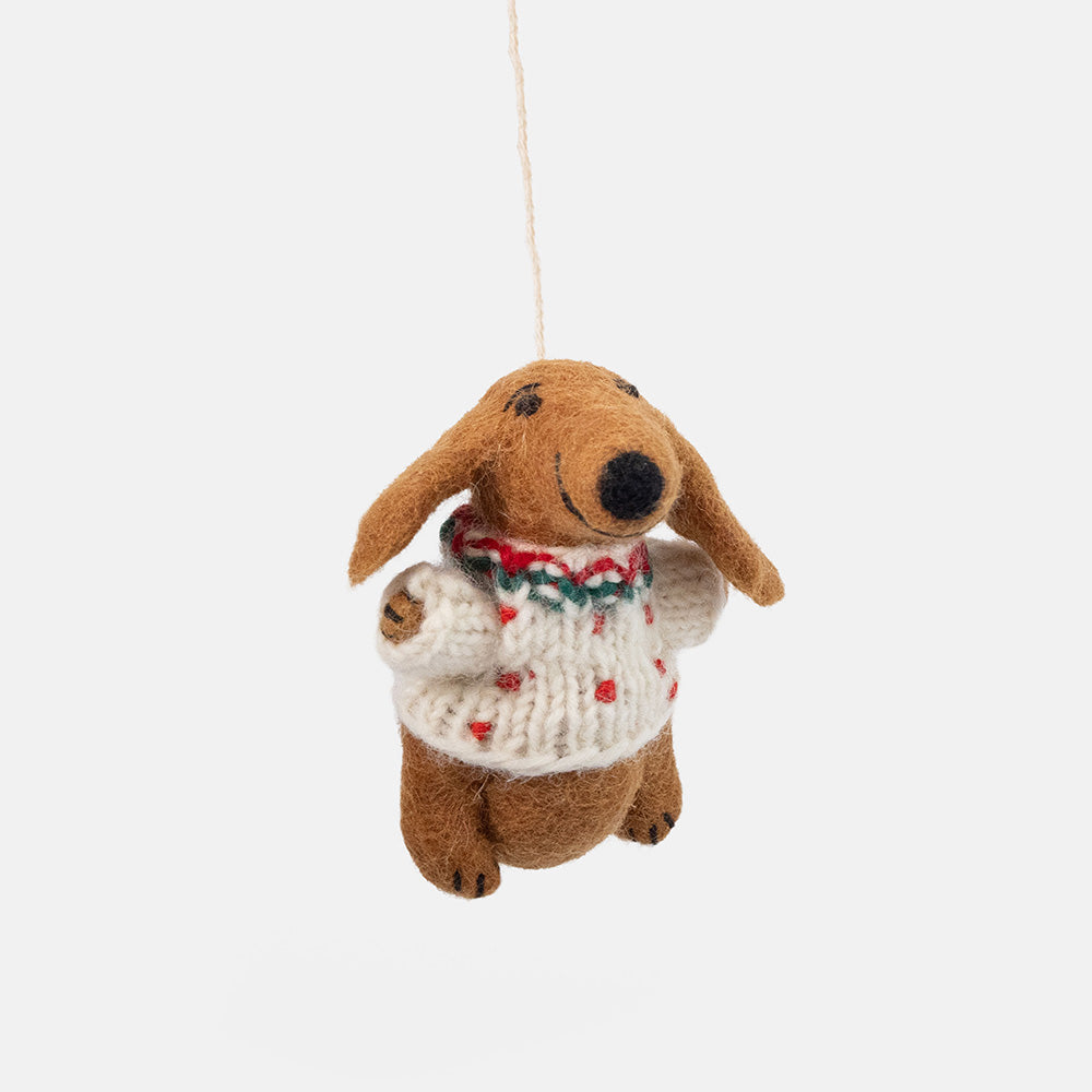 a felt sausage dog hanging Christmas tree decoration in a white wool jumper with red & green detailing, set against a white background