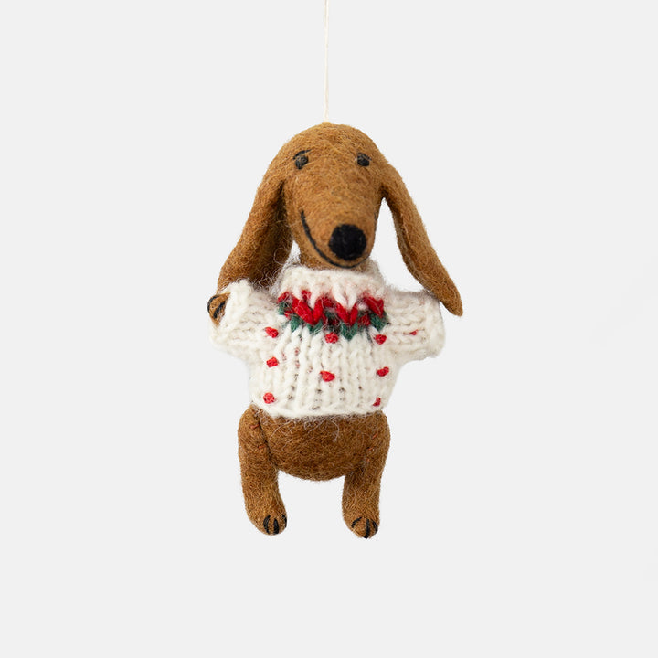 a felt sausage dog hanging Christmas tree decoration in a white wool jumper with red & green detailing, set against a white background
