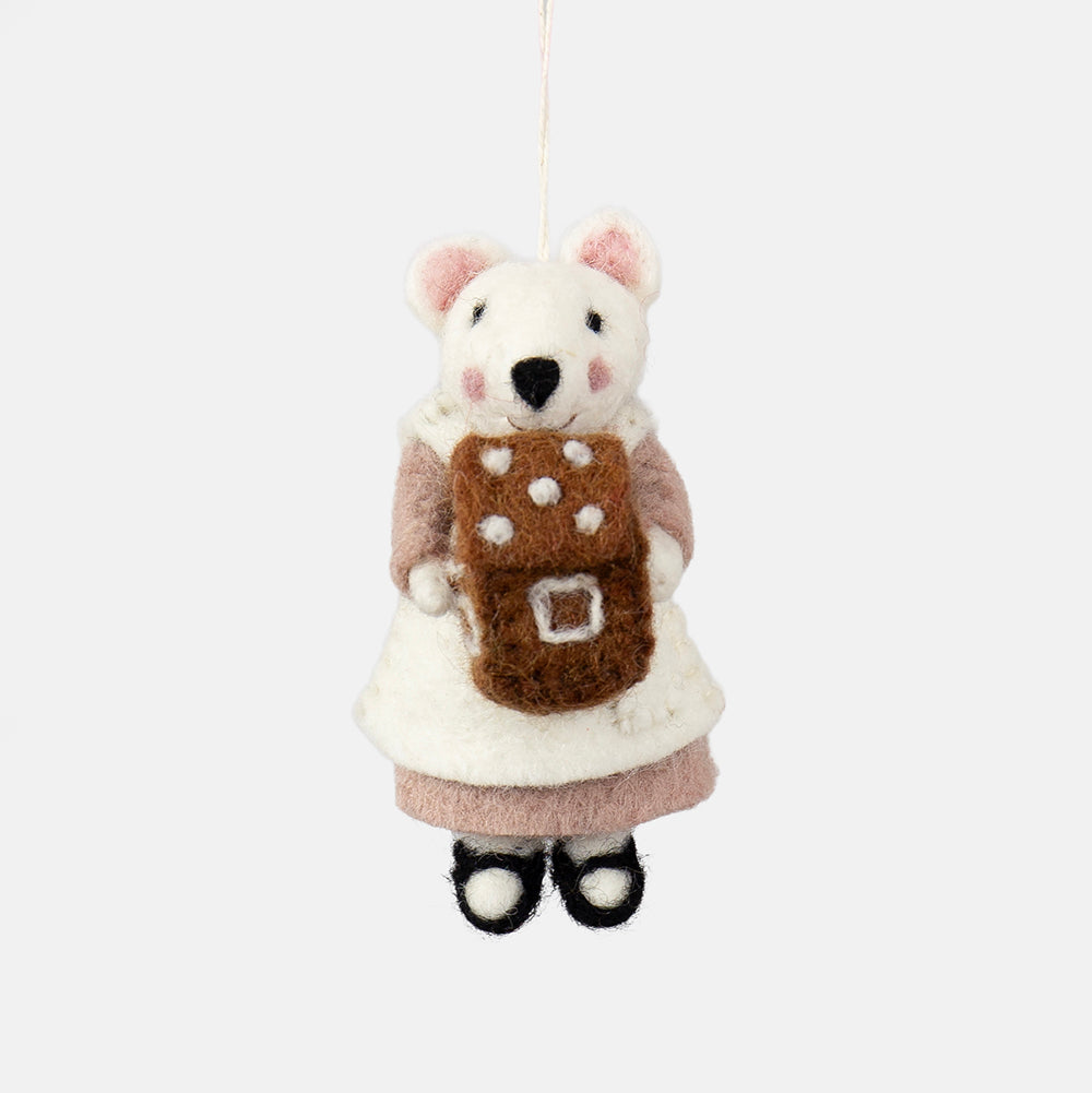 A felted wool mouse ornament wearing a white dress and pink sleeves, holding a brown gingerbread cookie with white polka dots, hanging against a plain light gray background.