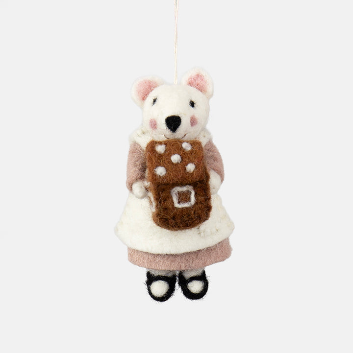 A felted wool mouse ornament wearing a white dress and pink sleeves, holding a brown gingerbread cookie with white polka dots, hanging against a plain light gray background.