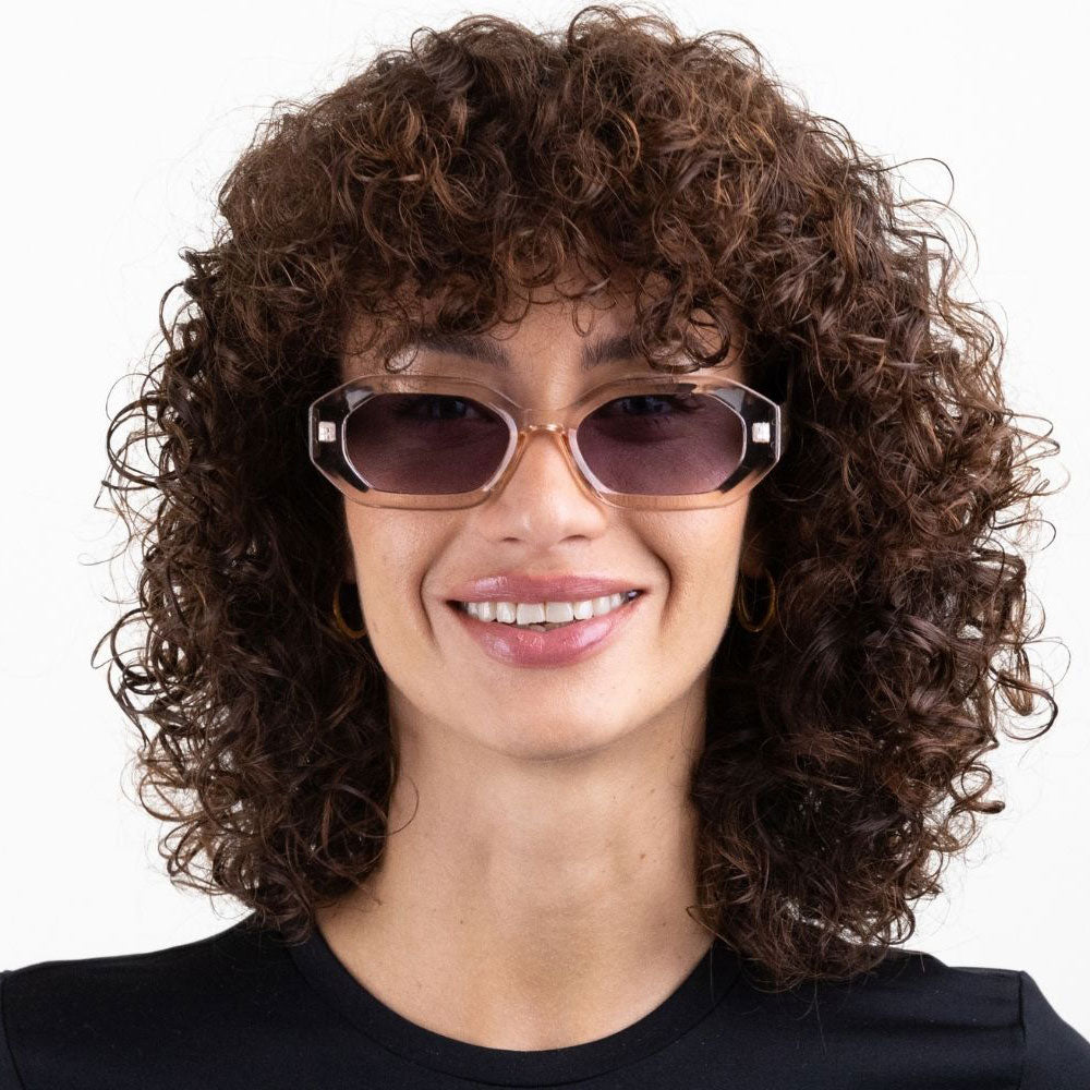 Person with curly hair wearing sunglasses on a white background