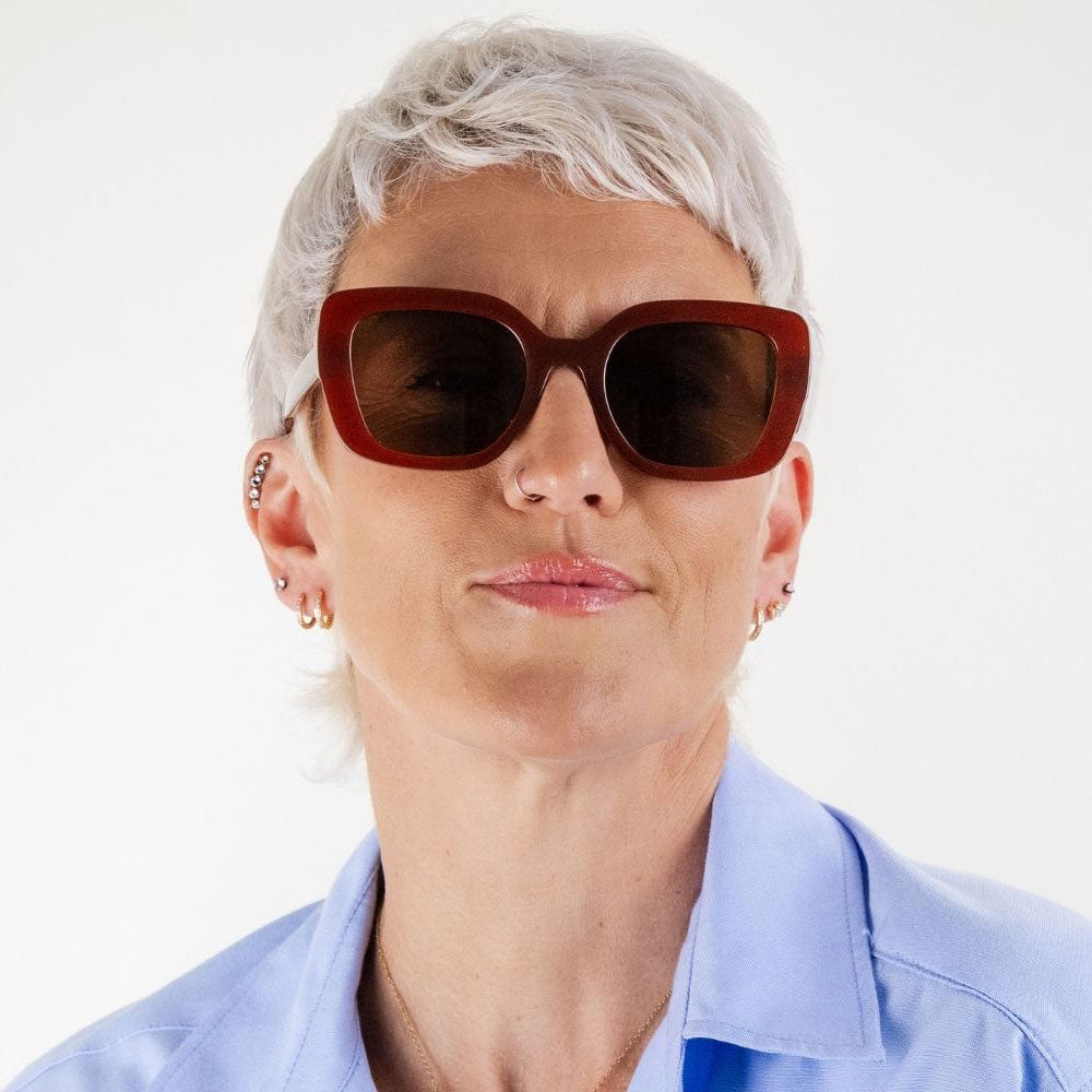 Person wearing sunglasses and a light blue shirt on a white background