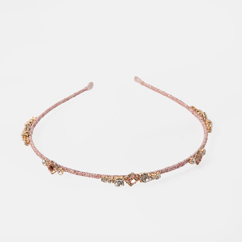 pink headband with decorative crystals on a light grey background