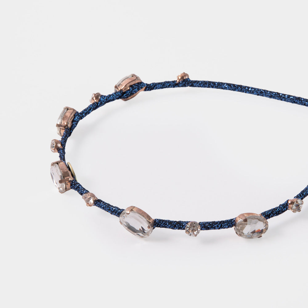 Navy blue headband with crystal-like beads on a white background