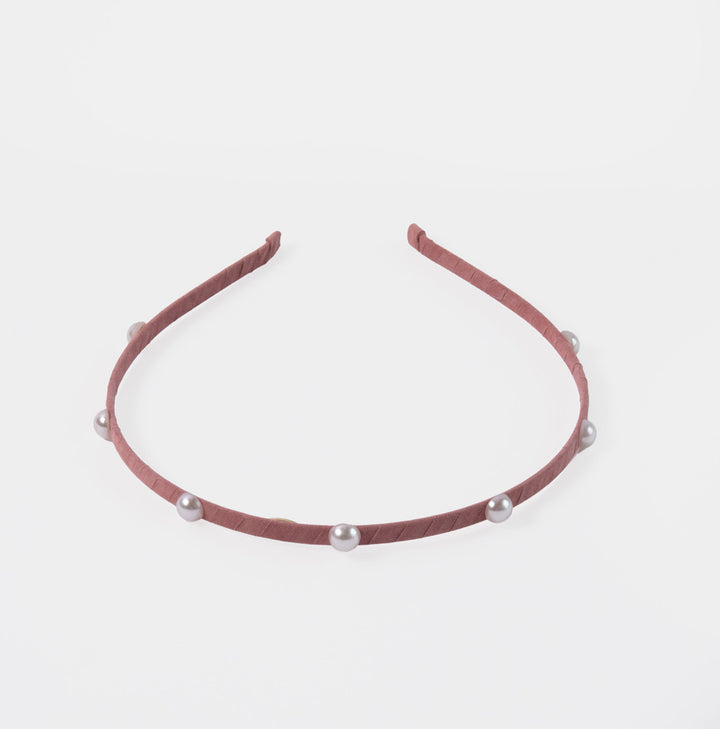 Pink headband with pearls on a light gray background