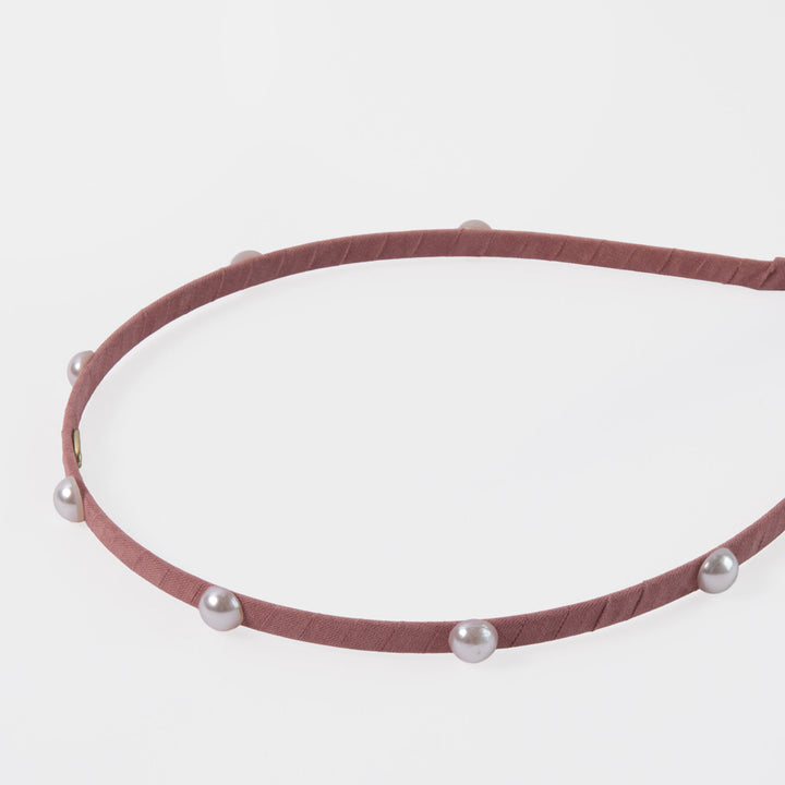 Pink headband with pearls on a light gray background