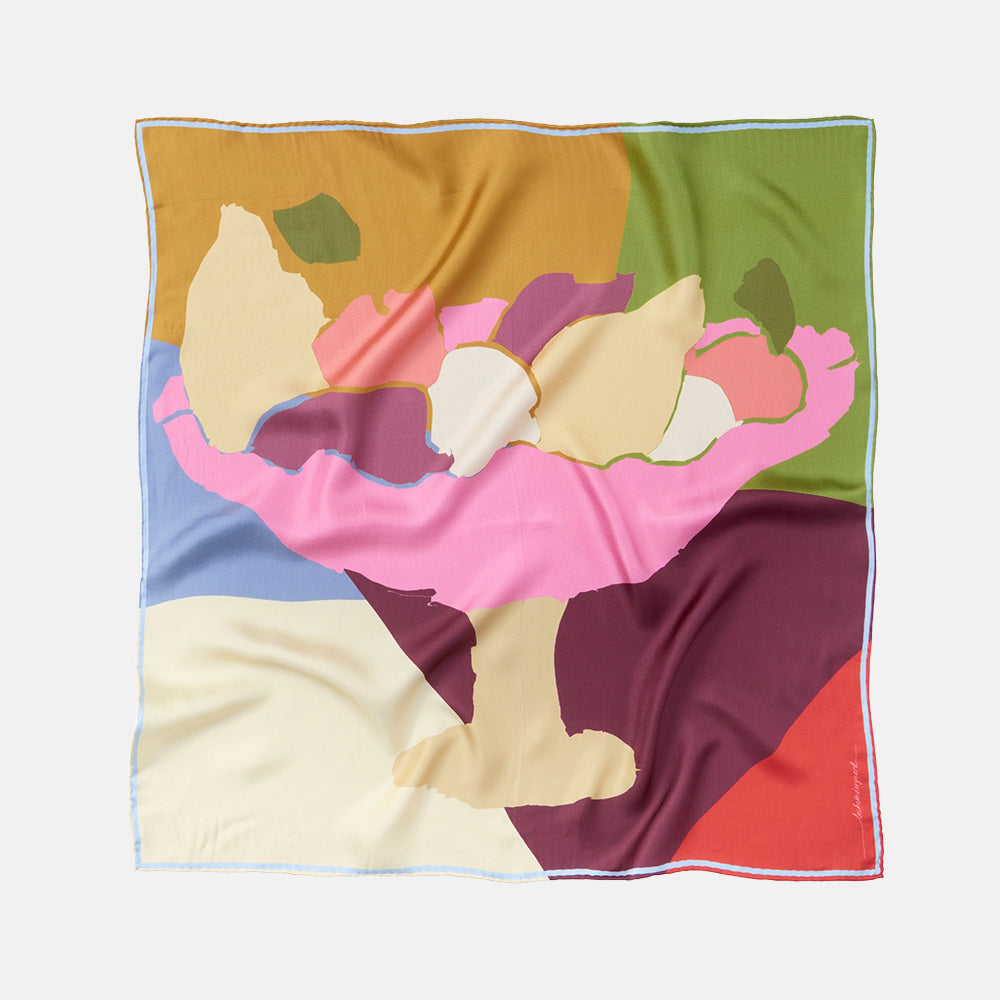 a square silk scarf with a colourful green, gold, pink, purple, red and cream abstract fruit bowl design