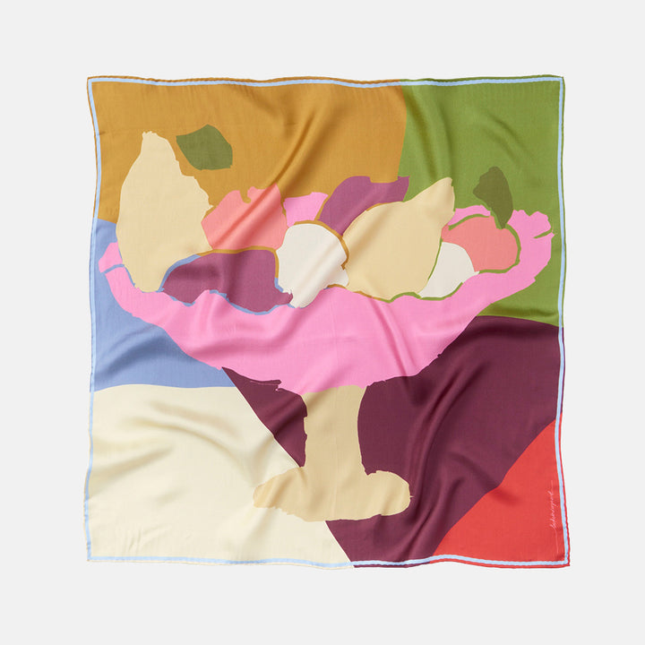 a square silk scarf with a colourful green, gold, pink, purple, red and cream abstract fruit bowl design