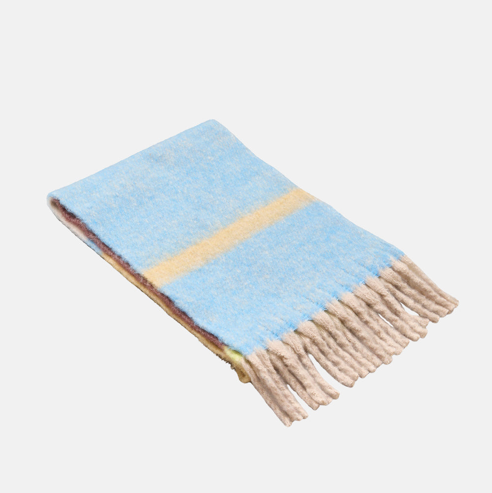 A brushed sky blue scarf with a yellow stripe and chunky oatmeal fringed ends, folded on a light grey background.