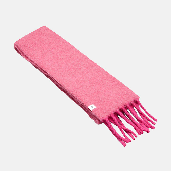 A slim, brushed raspberry pink scarf with fringed ends, laid flat on a light grey background.