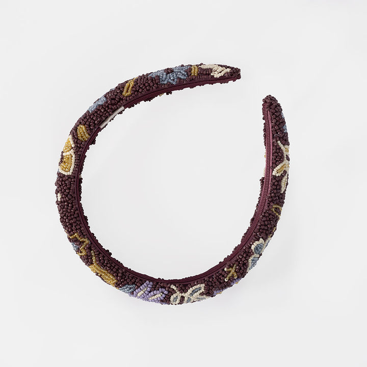 A wide, padded headband featuring a multicolor beaded floral pattern over a deep burgundy base, shown against a plain white background.