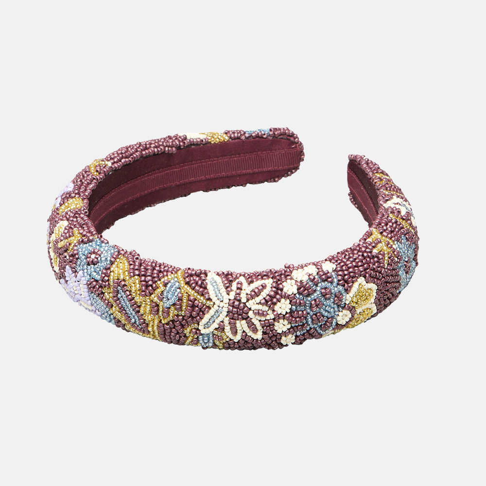 A wide, padded headband featuring a multicolor beaded floral pattern over a deep burgundy base, shown against a plain white background.