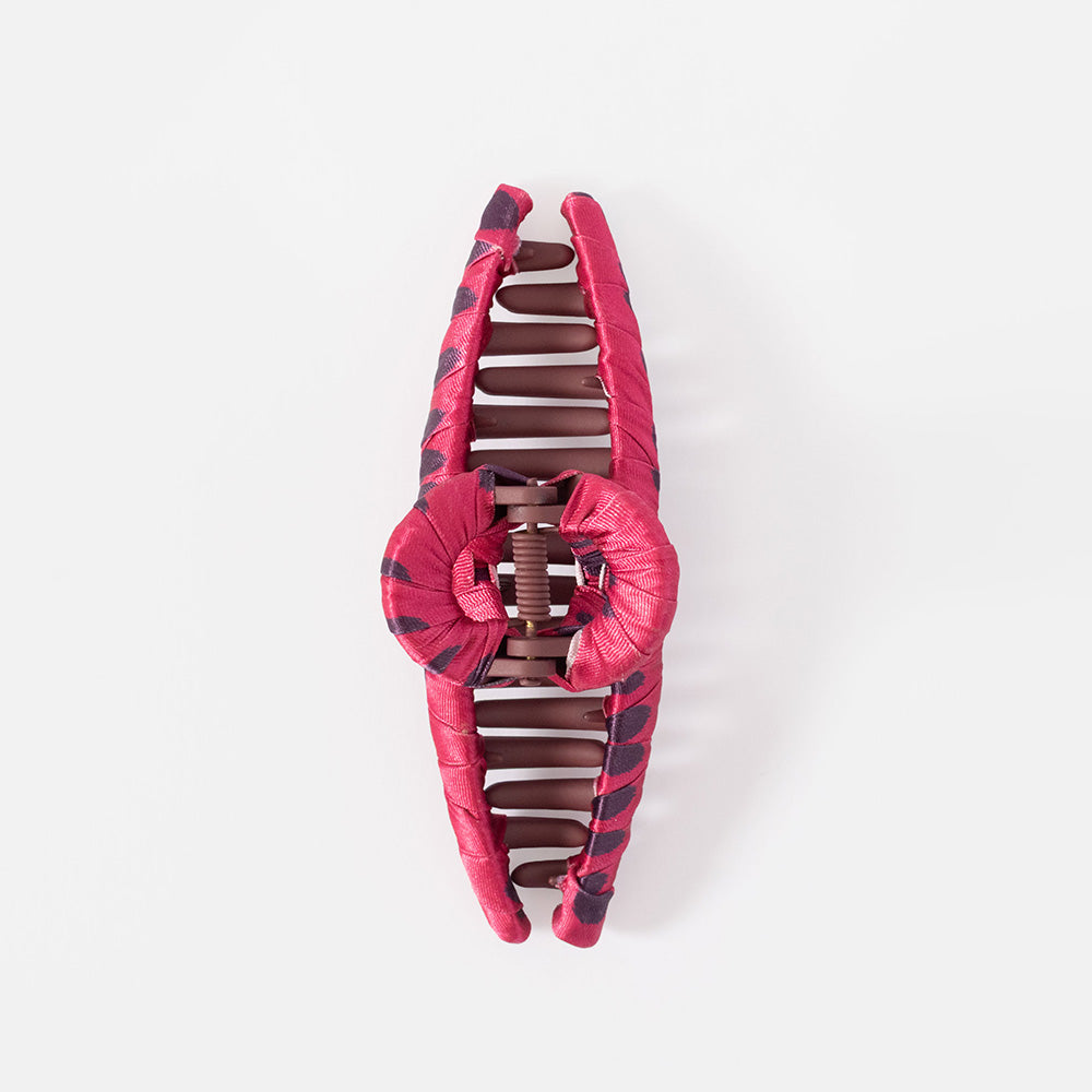 A large cotton claw hair clip in a glossy pink color, shown on a grey background.