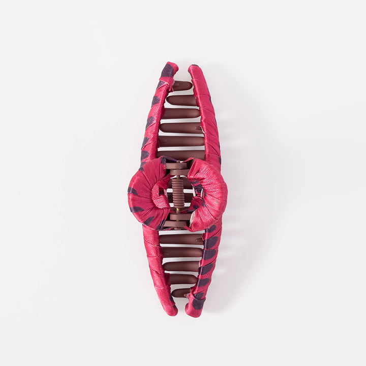 A large cotton claw hair clip in a glossy pink color, shown on a grey background.