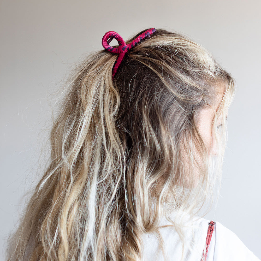 A large cotton claw hair clip in a glossy pink color, shown on a grey background.