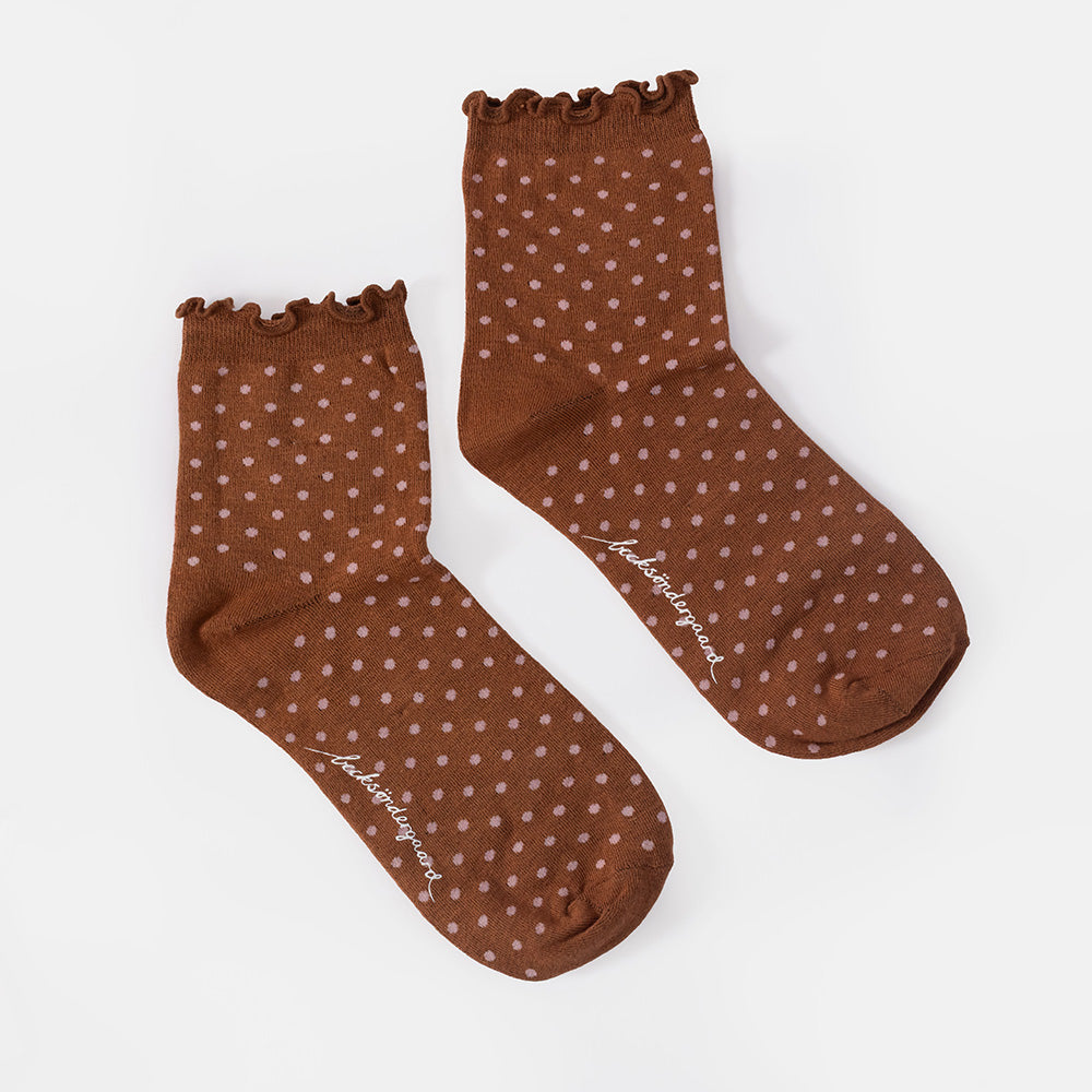 A single brown ankle sock with a pink polka dot pattern and a scalloped ruffled cuff, shown against a plain white background.