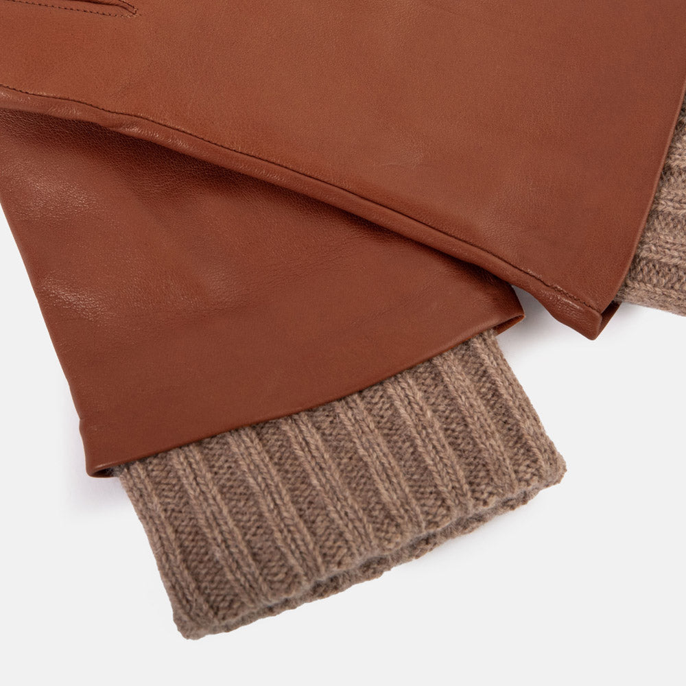 Close-up of a brown leather gloves with a ribbed knit cuff, shown on a clean white background.
