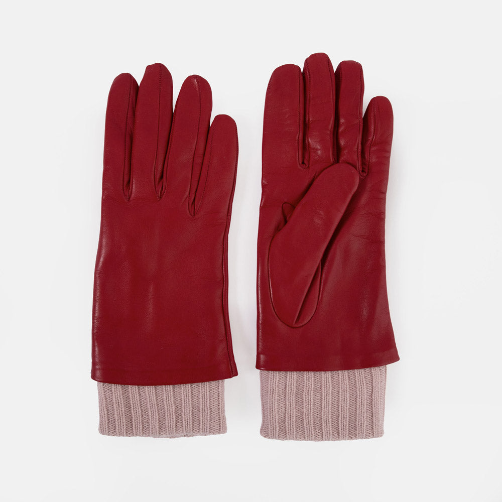 A pair of red leather gloves with ribbed knit cuffs in a dusty pink colour, displayed flat against a light grey background.