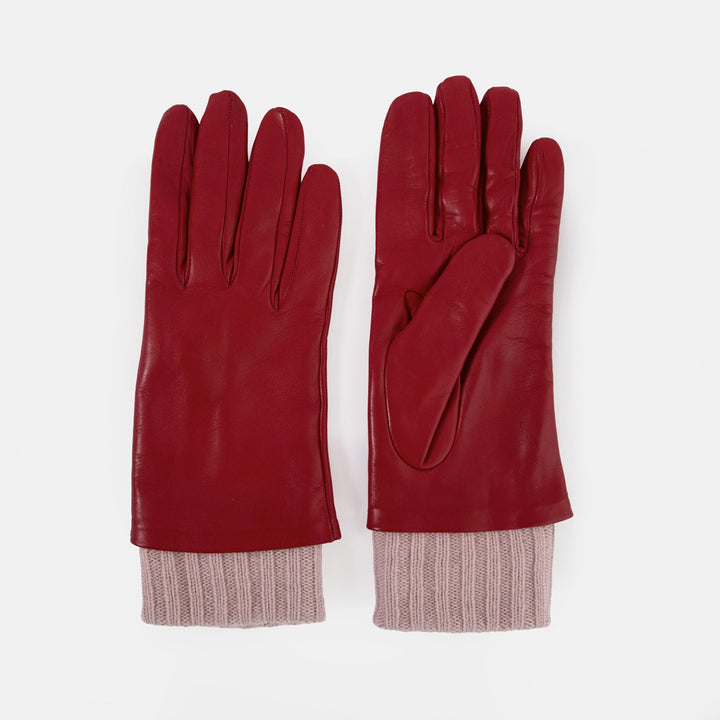 A pair of red leather gloves with ribbed knit cuffs in a dusty pink colour, displayed flat against a light grey background.